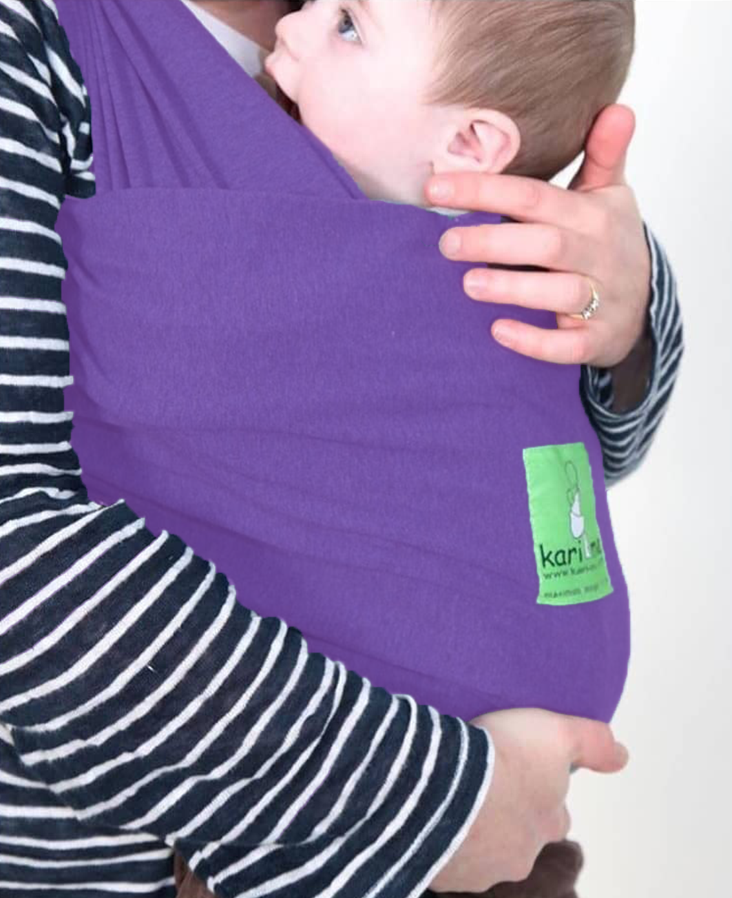 Person holding a baby in a purple baby carrier with a visible brand logo.