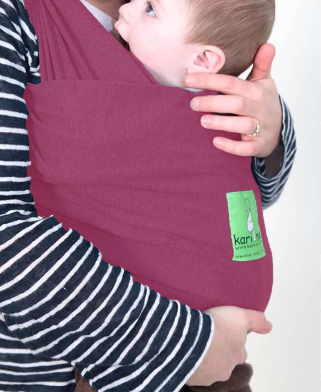 Person holding a baby in a maroon baby carrier with a visible brand logo.